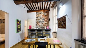 Un comedor acogedor con una mesa de madera, sillas negras y una pared de ladrillo.