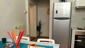 Uma cozinha com geladeira, forno e uma mesa de jantar com um tabuleiro de comida e um saco de petiscos.