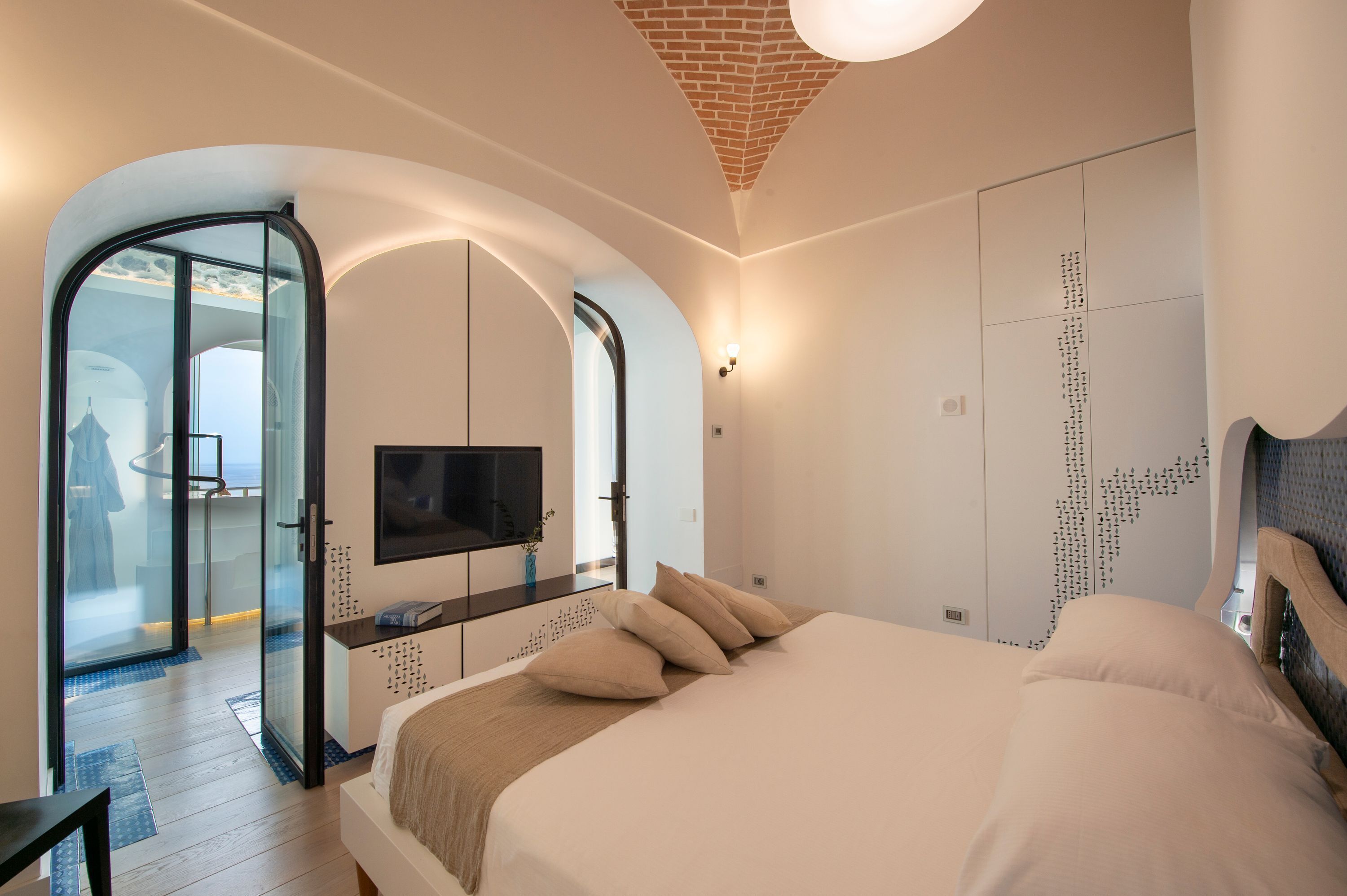 Une chambre d’hôtel moderne dotée d’un grand lit, d’une télévision et d’une porte vitrée donnant sur un balcon.