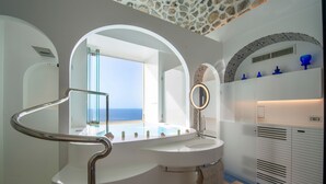 Ein modernes Badezimmer mit einem gebogenen Waschtisch, einem großen Spiegel und Blick aufs Meer.