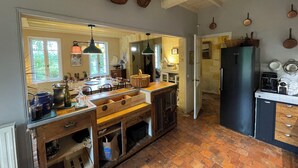 Une cuisine avec une table en bois, des paniers suspendus et un réfrigérateur noir.