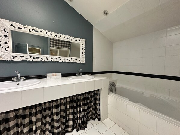 A bathroom with two sinks, a large mirror, and a bathtub.