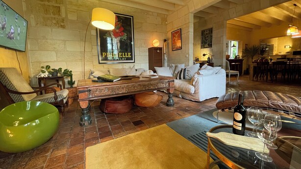 Un salon spacieux avec un mur en pierre, un grand tableau, une table basse en bois et un fauteuil en forme de haricot vert.
