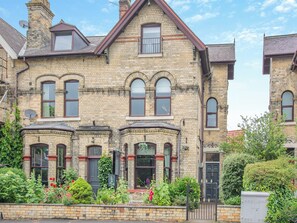 A Victorian-style brick house with multiple windows, a chimney, and a garden with various plants and flowers. - 6 bedroom accommodation in York (York)