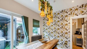 A dining area with a wooden table, hanging light fixtures, and a patterned wallpaper.