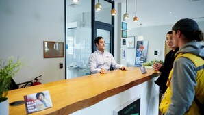 A reception desk with a wooden counter, a fire extinguisher, and a welcome sign. - Student Only Canvas Walthamstow in London (London)
