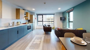 A modern kitchen with a dining area, large windows, and a view of buildings. - Student Only Canvas Walthamstow in London (London)