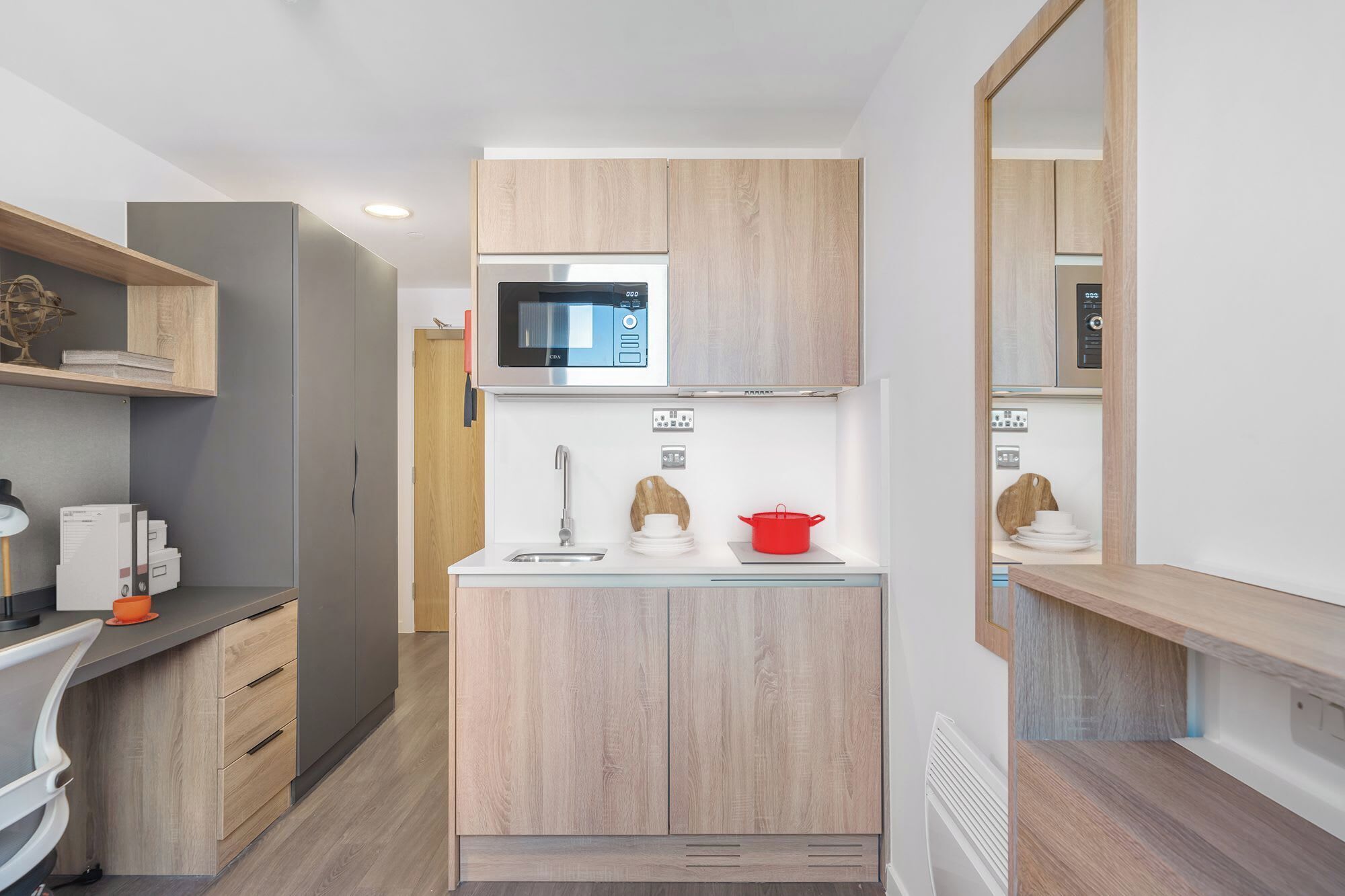 Una cocina pequeña con microondas, pileta y muebles de madera.