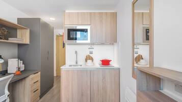 Una cocina pequeña con microondas, pileta y muebles de madera.