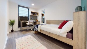 A modern bedroom with a bed, desk, chair, and a potted plant. - Student Only Canvas Walthamstow in London (London)