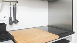 A kitchen with a wooden cutting board, black countertops, and hanging kitchen utensils. - Stunning, Bright Duplex (Saint-Ouen-sur-Seine)