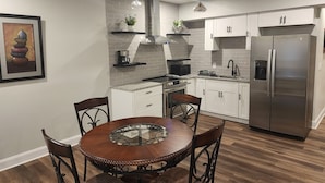 A modern kitchen with white cabinets, a stainless steel refrigerator, a gas stove, and a round dining table with chairs. - A luxurious getaway in beautiful Buford. (Buford)