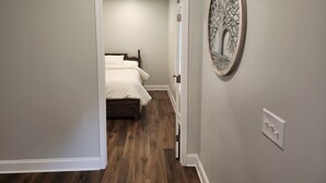 A narrow hallway leading to a bedroom with a bed and a wall-mounted tree decoration. - A luxurious getaway in beautiful Buford. (Buford)