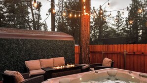A hot tub with a fire feature, surrounded by wicker furniture and a green wall. - Fully Remodeled Home Away From Home with all the amenities (Sugarloaf)