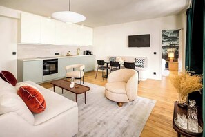 Uma sala de estar moderna com sofá, poltrona, mesa de centro e área de jantar com cadeiras e mesa.
