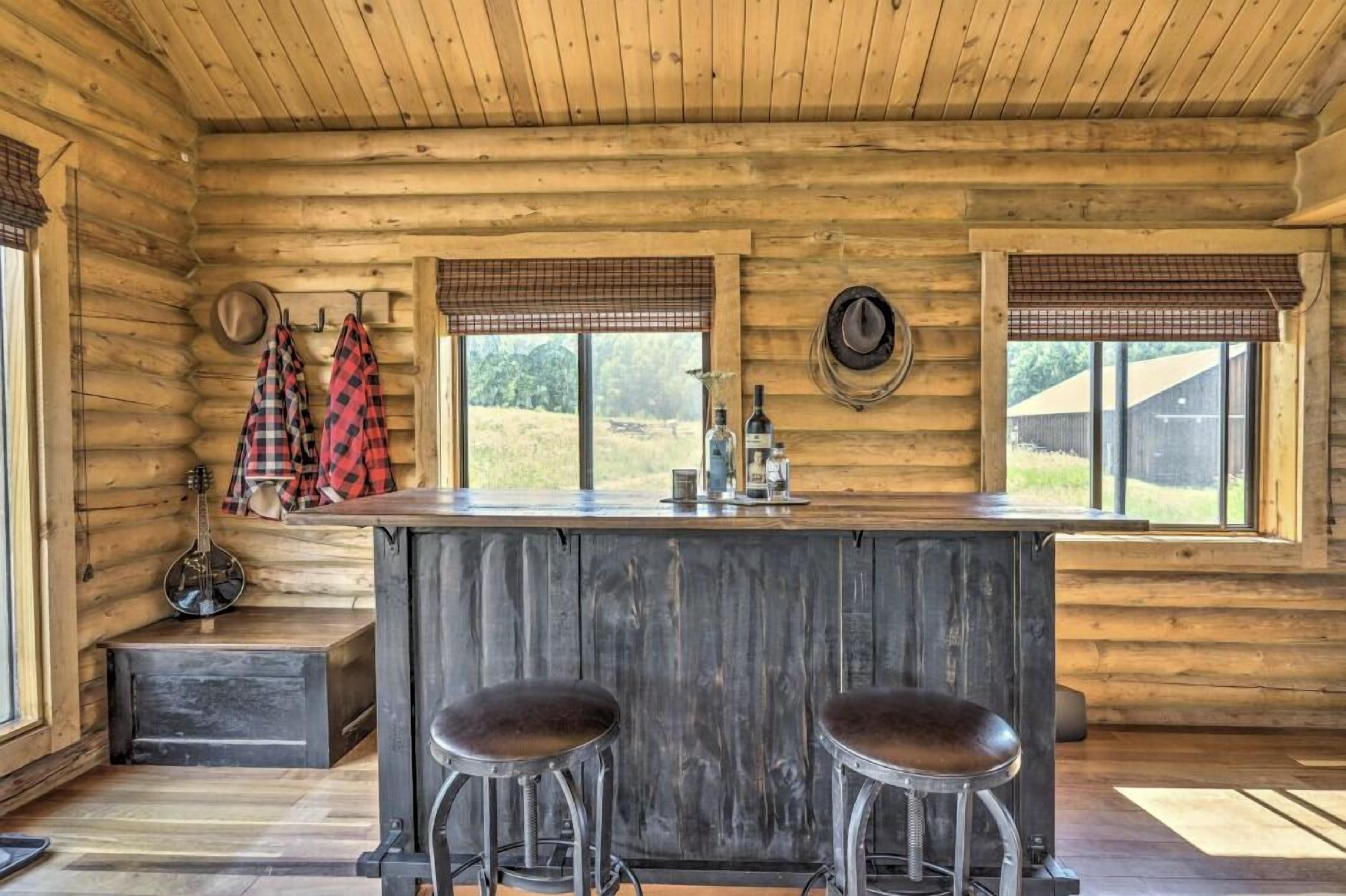 A rustic wooden cabin interior with a bar area, two stools, and a guitar.