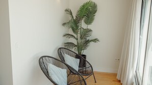 A room with two wicker chairs, a potted plant, and a large window with curtains. - Porto Panoramic Views With Terrace by Vacationy (Porto)