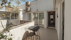A small patio area with a table and chairs, a tiled floor, and a view of the interior through a glass door. - Porto Panoramic Views With Terrace by Vacationy (Porto)