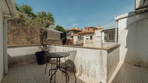 A small patio with a table and chairs, a potted plant, and a view of neighboring buildings. - Porto Panoramic Views With Terrace by Vacationy (Porto)