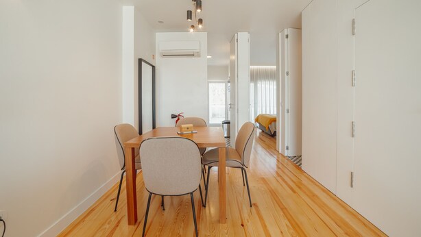 A modern dining area with a wooden table and chairs, an air conditioning unit, and a view into another room. - Porto Panoramic Views With Terrace by Vacationy (Porto)