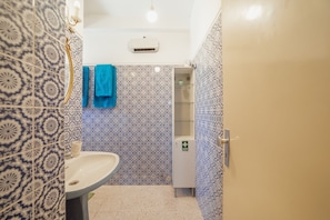 A bathroom with patterned tiles, a sink, a mirror, and a cabinet with a green sign. - Downtown Classic With Terrace by Vacationy (Porto)