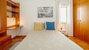 Une chambre à coucher comprenant un lit, une armoire en bois, une table de chevet et un tableau accroché au mur.