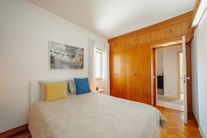 A bedroom with a bed, wooden wardrobe, and a painting on the wall. - Downtown Classic With Terrace by Vacationy (Porto)