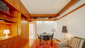 Un espace de vie compact comprenant un coin repas, un canapé et une petite table avec une lampe.