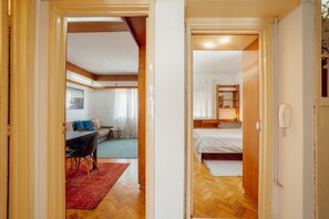 Een hotelkamer met een bed, een bureau en een stoel. Er is een raam met gordijnen, en een klein tafeltje met een stoel.