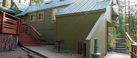 A rustic cabin with a metal roof, wooden stairs, and a small porch.