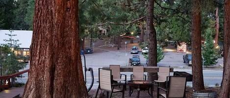 Een terras met tafels en stoelen, omgeven door bomen en lichtjes.