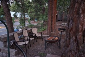 An outdoor seating area with wooden chairs and a fire pit. - Fox Den Suite in Shaver Lake (Shaver Lake)
