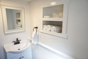 A bathroom with a white sink, mirror, and towel rack. - Fox Den Suite in Shaver Lake (Shaver Lake)