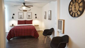 A bedroom with a bed, a large wall clock, framed pictures, and a ceiling fan. - Fox Den Suite in Shaver Lake (Shaver Lake)
