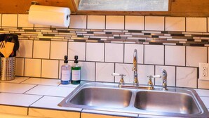 Une cuisine dotée d’une lucarne, d’un évier à deux bacs et d’un dosseret carrelé.