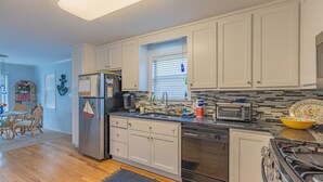 A modern kitchen with white cabinets, a stainless steel refrigerator, a built-in oven, and a microwave. - Bear Point Bayview Cottage – Bay Views, Marina Walk (Orange Beach)