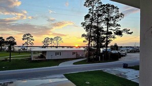 A residential area with a small house, a paved road, and a grassy area. - Bear Point Bayview Cottage – Bay Views, Marina Walk (Orange Beach)