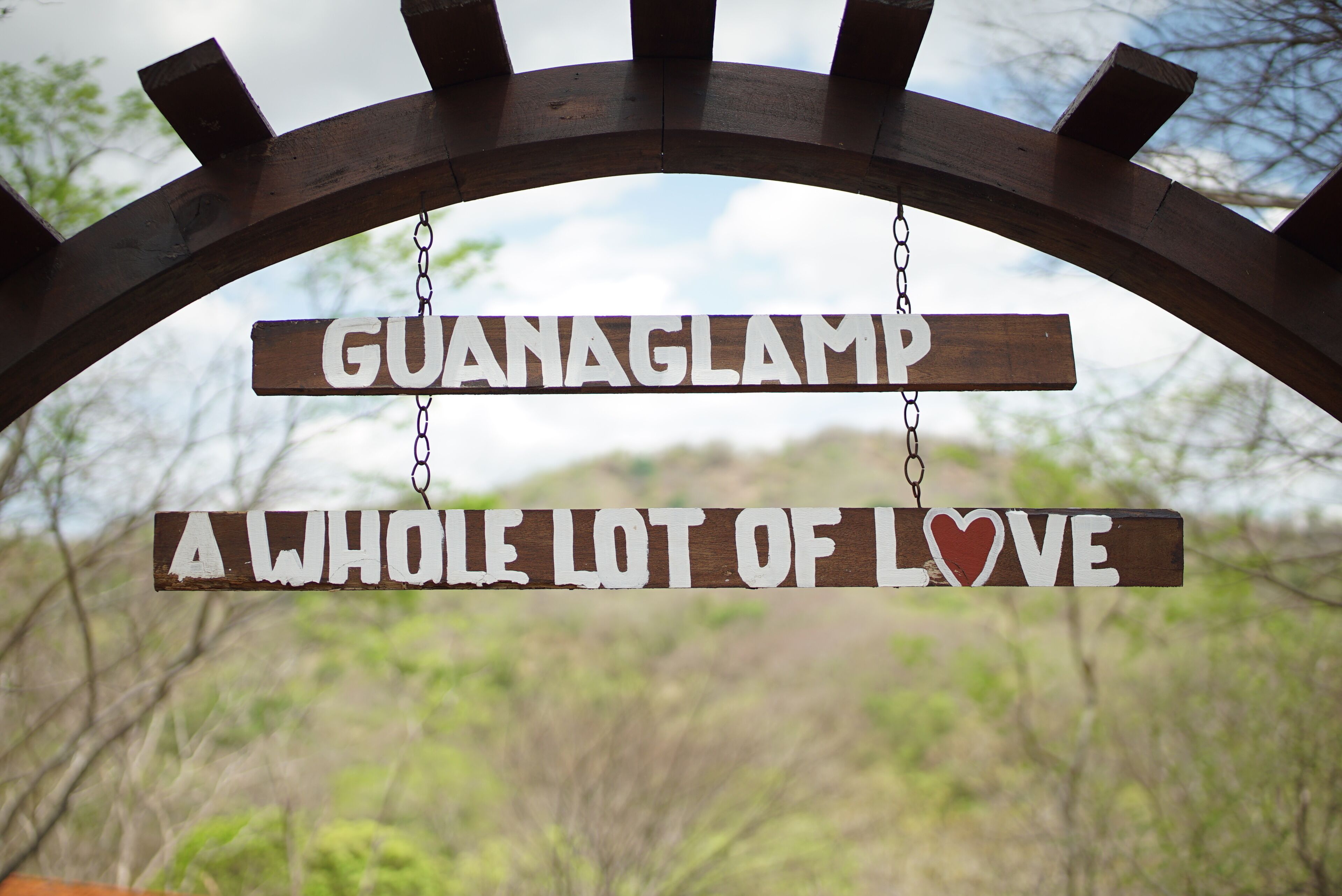 Un senyal de fusta amb el text “GUANAGLAMP” i “UN BUNDILL DE CARÍS” penjant d'una arcada de fusta.