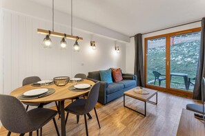 A modern dining area with a round wooden table, black chairs, and a blue sofa.