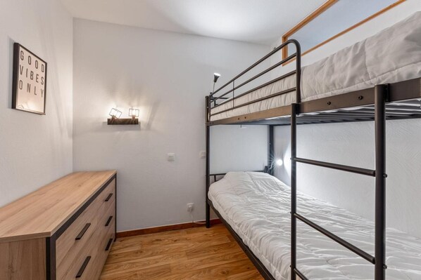 A bunk bed room with a wooden dresser and wall-mounted lights.