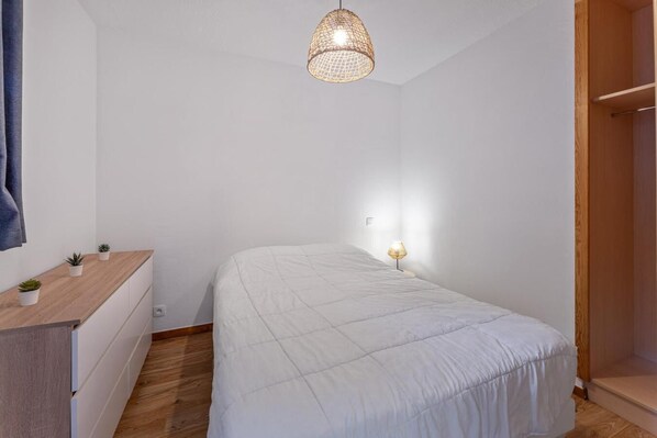 A bedroom with a bed, bedside table, lamp, and a hanging light fixture.