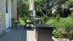 A wooden deck with a table and chairs, a grill, and a basket. -  Edgartown cottage in a garden setting.  New and near bike path in Katama (Edgartown)