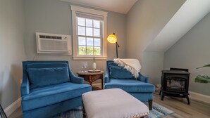 A cozy living room with two blue armchairs, a small table, a lamp, and a fireplace. -  Edgartown cottage in a garden setting.  New and near bike path in Katama (Edgartown)