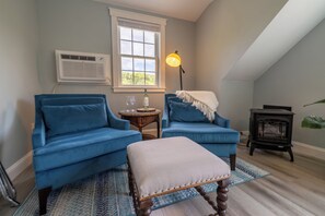 A cozy living room with two blue armchairs, a small table, a lamp, and a fireplace.