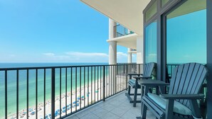 A balcony with a view of the beach, featuring a railing and two Adirondack chairs. - 1605 3bd Oasis Beach Paradise - OasisAtOrangeBeach (Orange Beach)