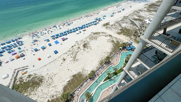 An aerial view of a beach with numerous umbrellas and a swimming pool area. - 1605 3bd Oasis Beach Paradise - OasisAtOrangeBeach (Orange Beach)