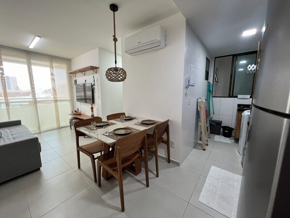 Una cucina moderna con zona pranzo, caratterizzata da un tavolo grande, sedie in legno e una lampada a sospensione.
