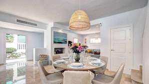 Un espace repas moderne avec une table ronde, six chaises et un luminaire suspendu.