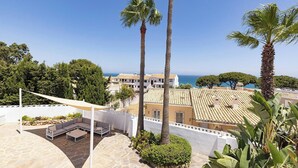 Une terrasse sur le toit dotée d’un sol en pierre incurvé, d’une pergola blanche et d’un espace salon avec des coussins.