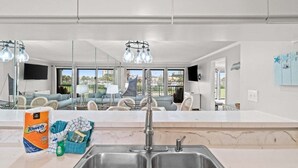 A modern kitchen with a double sink, a large window, and a view of the outdoors. - Fall Deals + Snowbird Rates | Coastal Stay Near the Beach (Panama City Beach)